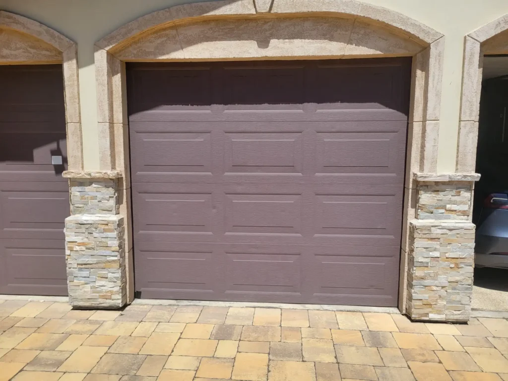 Modern brown garage door installed with stone trim in a driveway